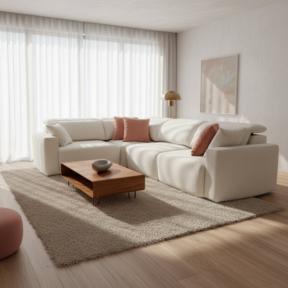 Sofá rinconera de tela blanca en salón con librería disponible en Sidivani